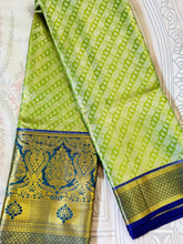 Green and gold saree with a blue border on a white background