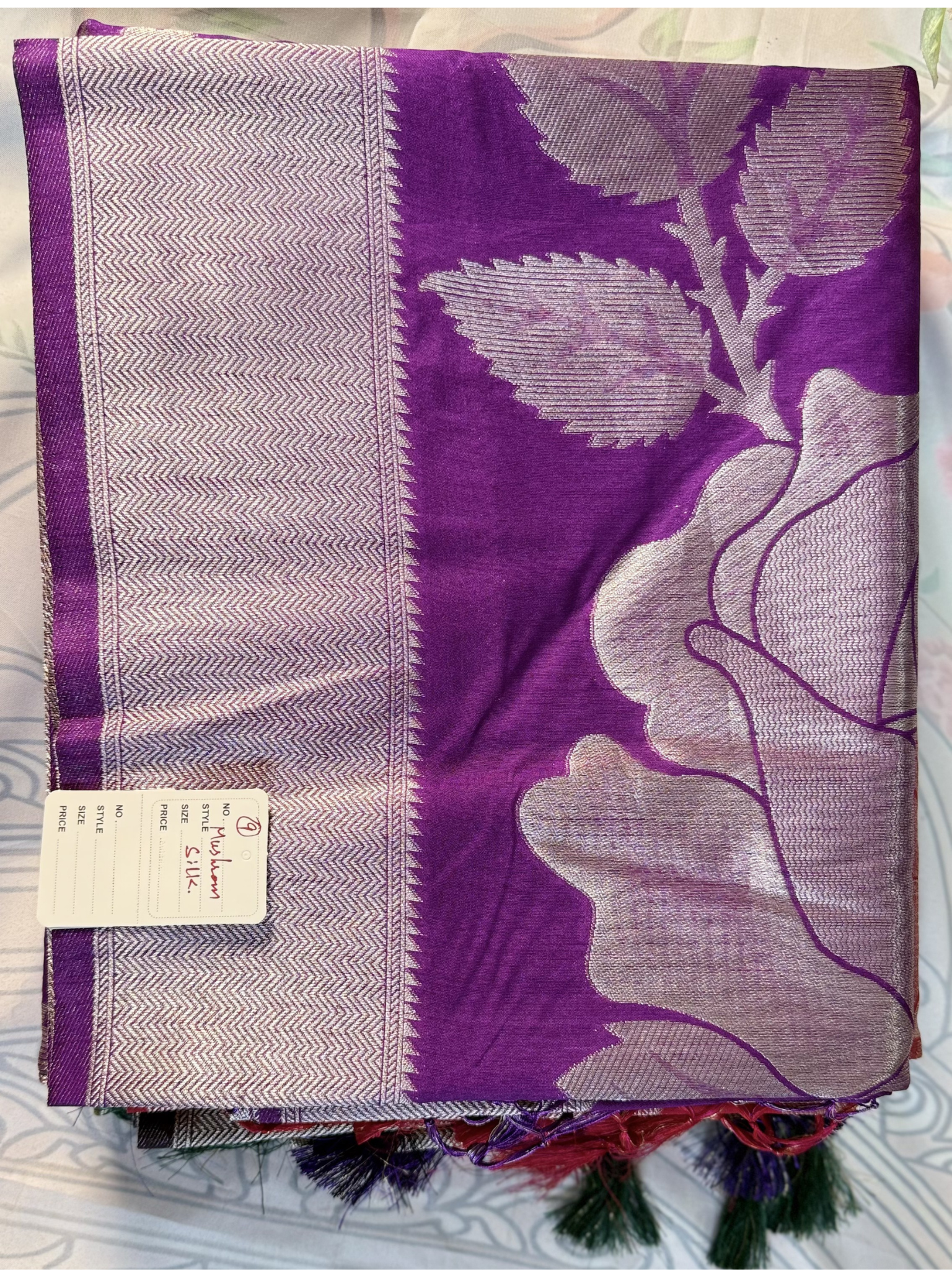 Purple scarf with floral design and brand tag on a white background