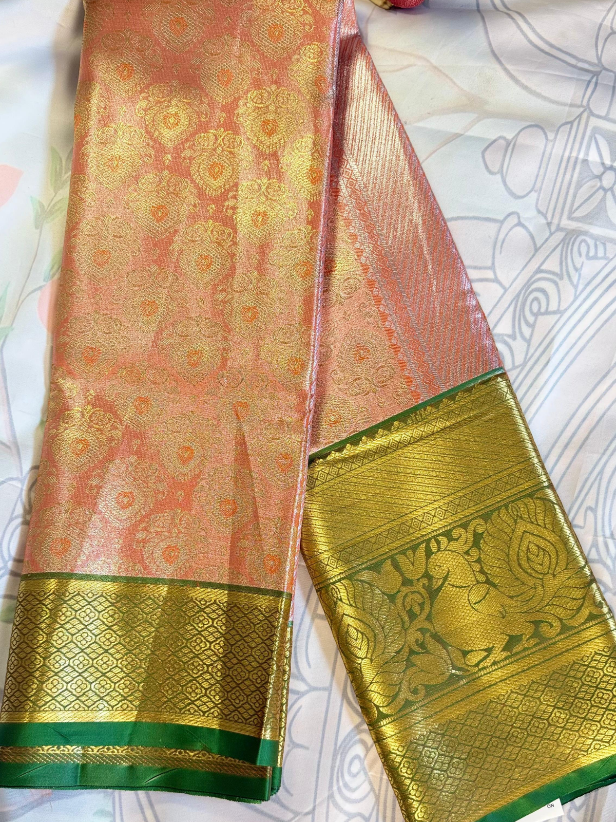 Traditional saree with pink and green patterns on a white background