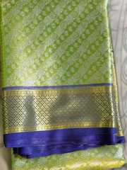 Green saree with gold and blue border on a neutral background