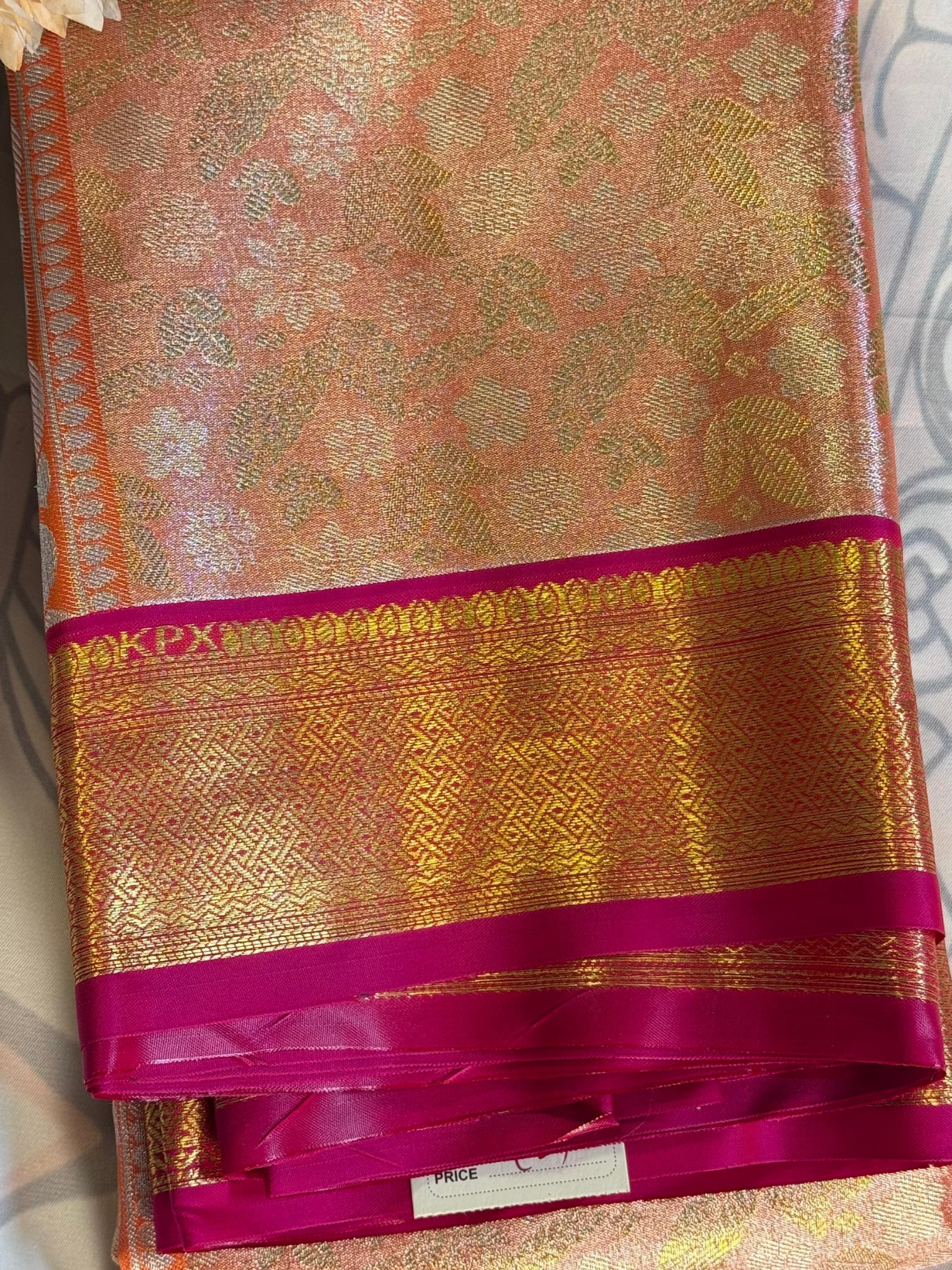 Gold and pink saree with intricate patterns on a plain background