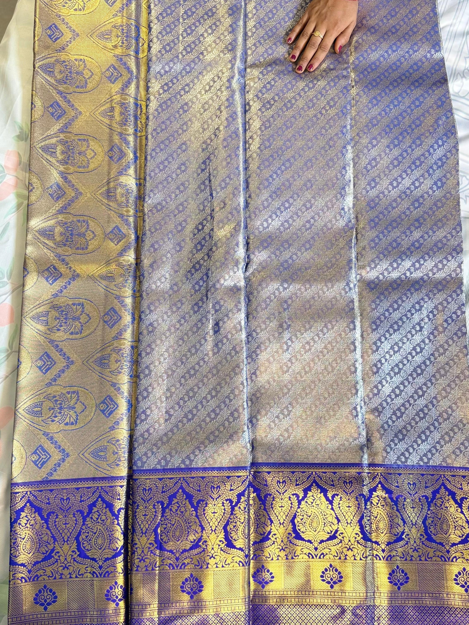 Saree with intricate patterns and a hand holding it