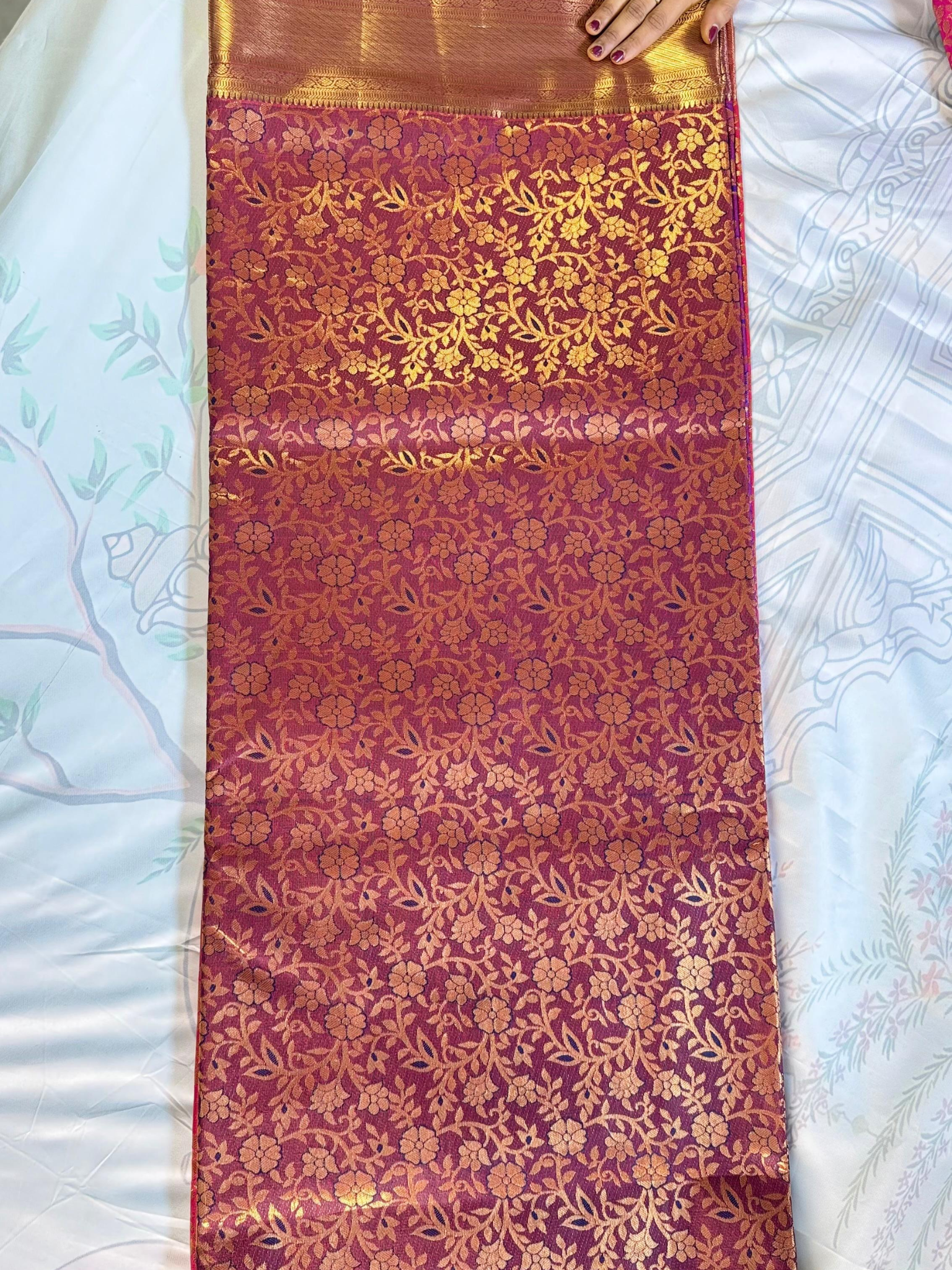 Red fabric with gold floral patterns on a white surface