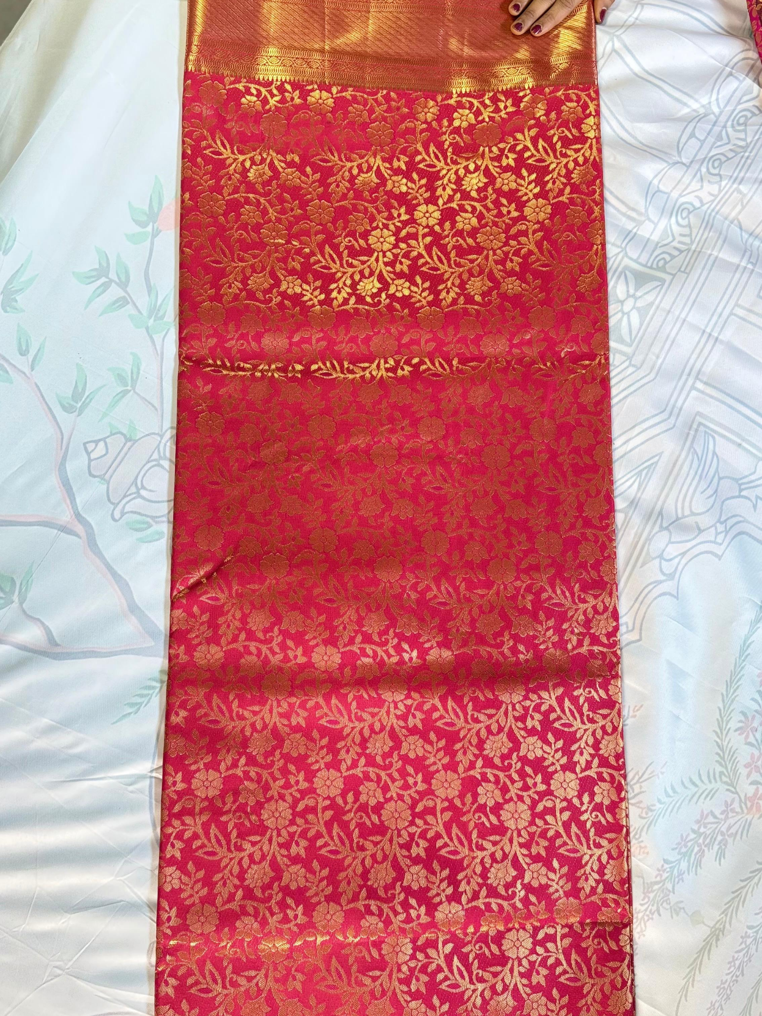 Red saree with gold floral patterns on a white background